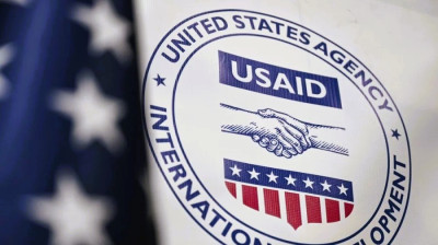 USAID logo on a sign with an American flag in the background.