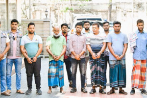 Group of arrested suspects in the Dhaka gold heist case, standing with law enforcement officers.