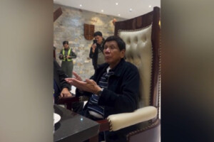 Former Philippine President Rodrigo Duterte questions ICC arrest warrant while seated in a high-backed chair.
