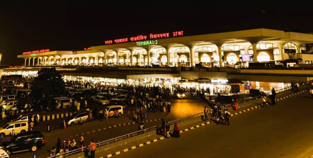 Hazrat Shahjalal International Airport in Dhaka at night, crowded with passengers and vehicles.