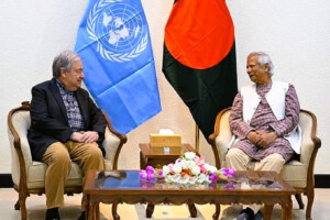 UN Secretary-General António Guterres meets with Bangladesh's Chief Adviser Prof. Muhammad Yunus in Dhaka, with the UN and Bangladesh flags in the background.