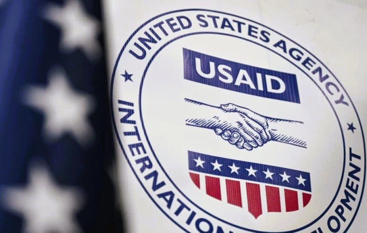 USAID logo on a sign with an American flag in the background.