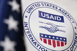 USAID logo on a sign with an American flag in the background.