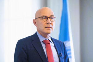 UN High Commissioner for Human Rights Volker Türk speaking at an event, with a UN flag in the background.